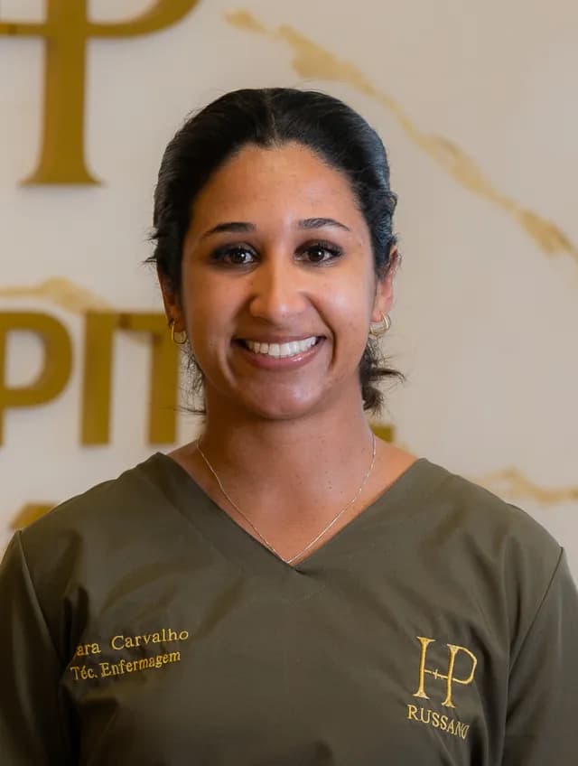 Dara Carvalho, de cabelo preto preso e uniforme verde-oliva, sorrindo