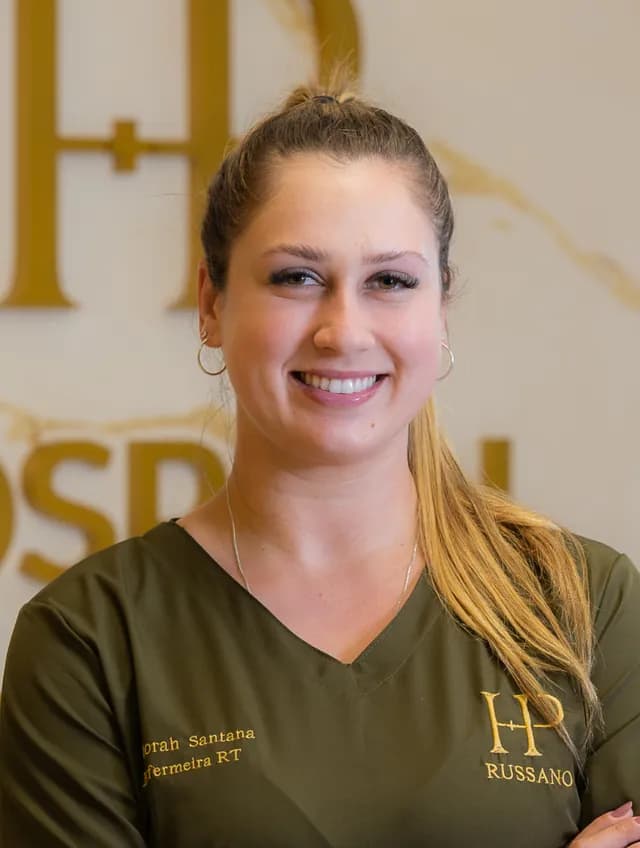 Déborah Santana, de uniforme verde-oliva, sorrindo de braços cruzados