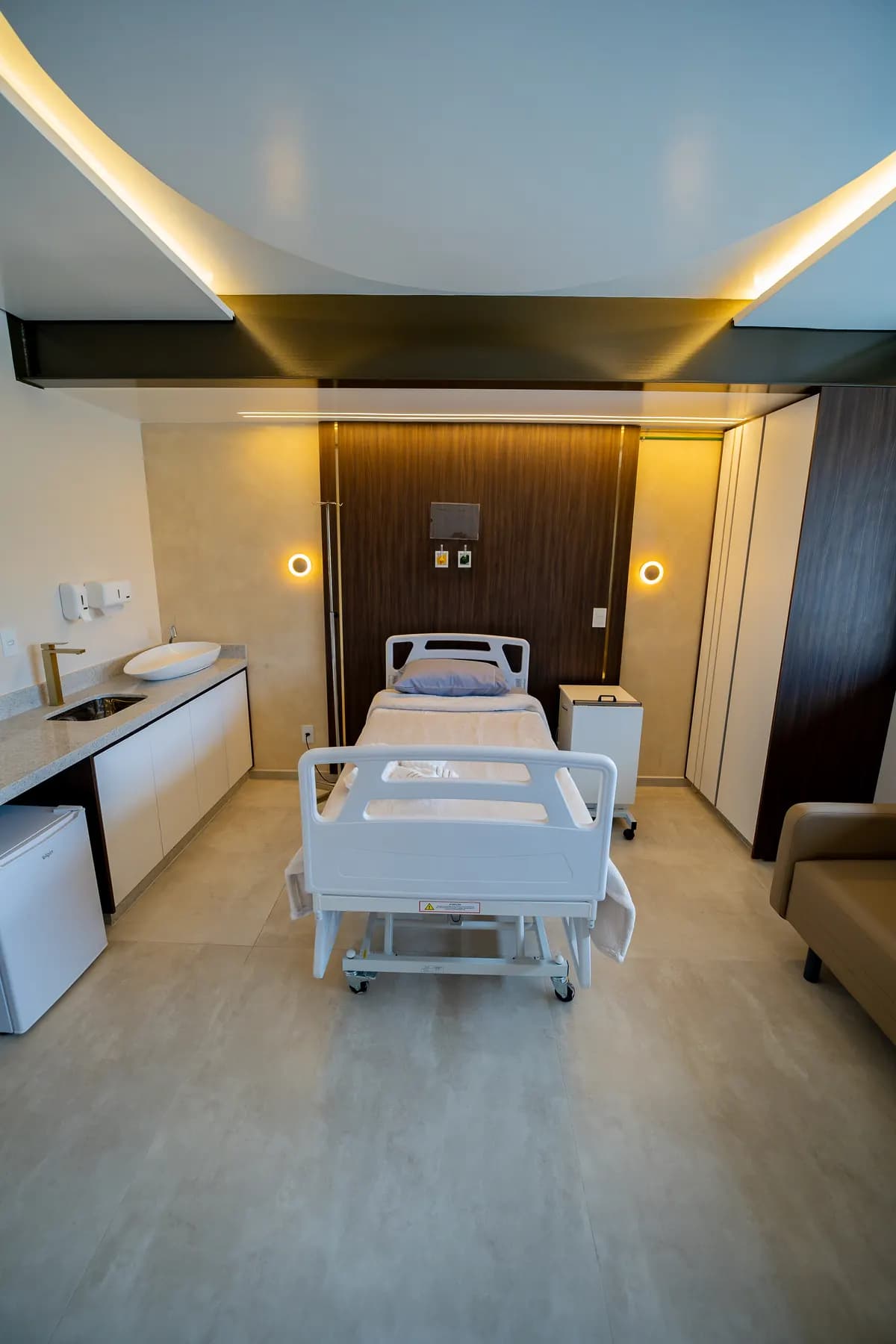 Leito hospitalar, bancada e armários no quarto de internação