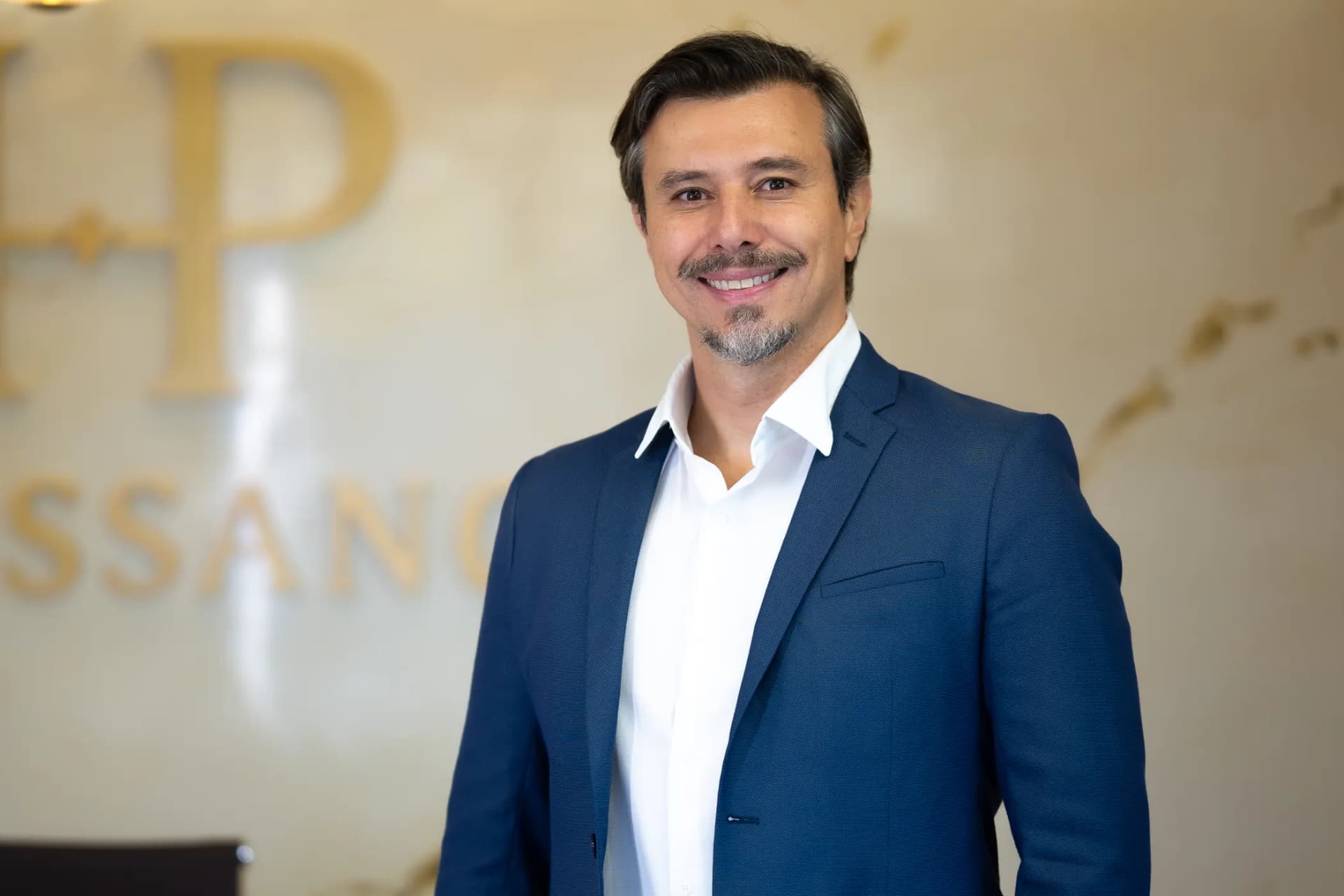 Dr. Mário Russano de blazer azul sorrindo na recepção do hospital
